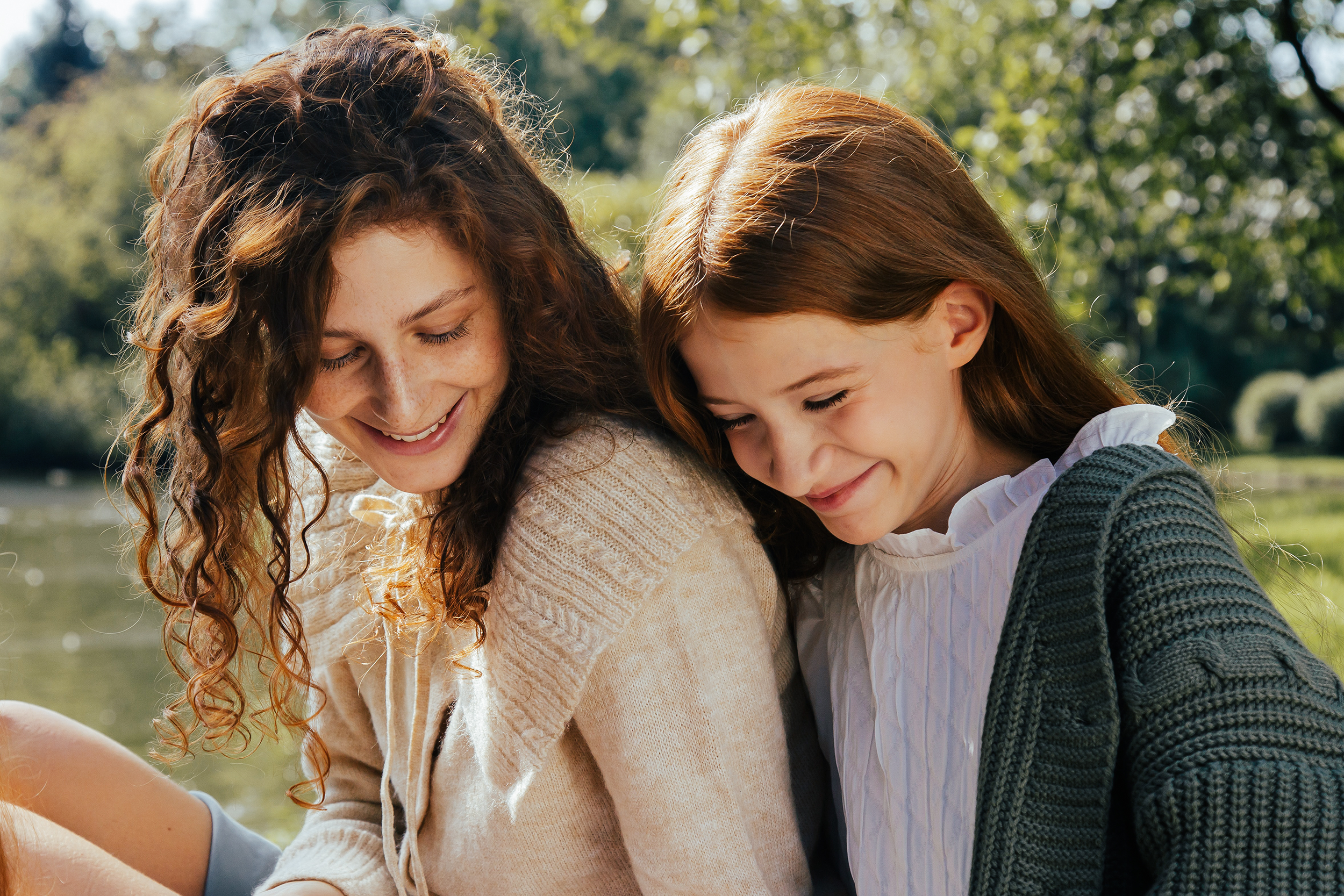 Mother and teen girl sitting together outside